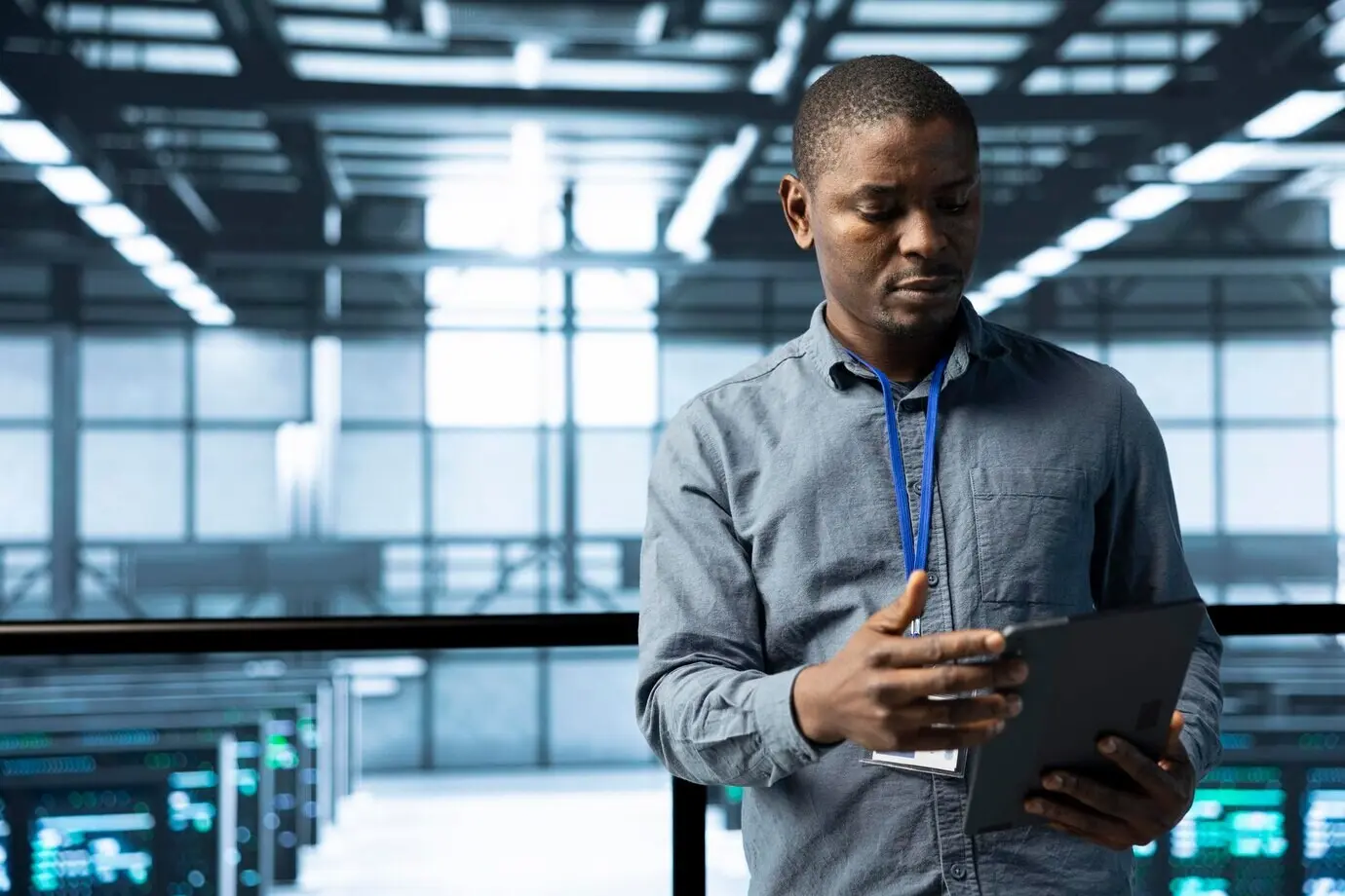 В дата-центре специалист по информатике с помощью планшета проверяет соответствие стоек требованиям.